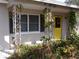 Inviting front porch featuring decorative columns, a window with shutters, and a bright yellow front door at 2895 Huntington Dr, Largo, FL 33771