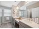 Bright bathroom featuring a large mirror, double vanity with quartz countertop and tiled floors at 29917 Southwell Ln, Wesley Chapel, FL 33543