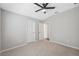 Empty bedroom with neutral walls and carpet, featuring a ceiling fan and two doors at 29917 Southwell Ln, Wesley Chapel, FL 33543