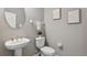 Modern half bathroom with pedestal sink, toilet, and neutral wall color, complemented by decorative wall art at 29917 Southwell Ln, Wesley Chapel, FL 33543