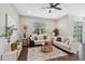 Bright living room featuring comfortable sofas, a ceiling fan, and a large window for natural light and view of the exterior at 29917 Southwell Ln, Wesley Chapel, FL 33543