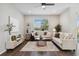 Bright living room featuring comfortable sofas, a ceiling fan, and a large window for natural light and view of the exterior at 29917 Southwell Ln, Wesley Chapel, FL 33543