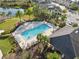Aerial view of a beautiful community pool with ample lounge seating, adjacent to a serene lake and well-manicured landscaping at 29917 Southwell Ln, Wesley Chapel, FL 33543