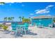 Exterior view of the clubhouse with light-blue picnic tables and seating, palm trees, and beautiful landscaping at 4007 Floramar Ter, New Port Richey, FL 34652