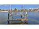 Wooden boat lift sitting over canal water on a sunny day with neighborhood homes in the background at 4529 Flounder Dr, Hernando Beach, FL 34607