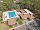 Aerial view of a community pool, clubhouse, and tennis courts amidst lush greenery and ample parking at 6002 Laketree Ln # L, Temple Terrace, FL 33617