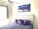 Bedroom with ceiling fan, window and a bed with purple accent pillows and tree art at 6734 Dali Ave # 205, Land O Lakes, FL 34637