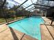 Backyard pool area with screened-in enclosure, brick pavers, and a refreshing pool at 7090 Red Oak Loop, New Port Richey, FL 34654