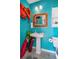 Beach-themed bathroom with a pedestal sink, decorative mirror, and vibrant turquoise walls at 7235 Maryland Ave, Hudson, FL 34667