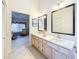 Bright bathroom featuring double sinks, framed mirrors, and a view into a carpeted bedroom at 8447 Pavilion Dr, Hudson, FL 34667