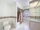 Bathroom with shower/tub, toilet, vanity, tropical-themed decor, and neutral tile at 8447 Pavilion Dr, Hudson, FL 34667