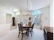 Bright dining room features large windows, chandelier lighting, and a wooden dining table with seating for four at 8447 Pavilion Dr, Hudson, FL 34667