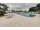 Community pool with lounge chairs surrounded by a white fence and mature trees at 8447 Pavilion Dr, Hudson, FL 34667