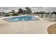 Community pool with lounge chairs surrounded by a white fence and mature trees at 8447 Pavilion Dr, Hudson, FL 34667