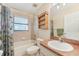 Bathroom boasts tiled shower, toilet, and sink with storage shelf and nautical-themed shower curtain at 13083 Jaywalk Rd, Brooksville, FL 34614