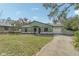 Exterior front view of light-green house with front lawn, red door, and attached garage at 13083 Jaywalk Rd, Weeki Wachee, FL 34614