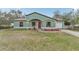 Exterior front view of light-green house with front lawn, red door, and attached garage at 13083 Jaywalk Rd, Brooksville, FL 34614