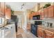 Functional kitchen featuring wooden cabinets, granite countertops, and black appliances at 13083 Jaywalk Rd, Brooksville, FL 34614
