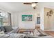 Bright living room with a gray sofa, large window, and a flat-screen TV mounted on the wall at 13083 Jaywalk Rd, Brooksville, FL 34614