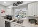 Kitchen with stainless steel sink, white cabinets, and an open view to the outdoor seating area at 2862 Lomond Dr, Palm Harbor, FL 34684
