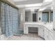 Bright bathroom featuring a shower with blue patterned curtain, vanity with white cabinets and a large mirror at 4603 Lake In The Woods Dr, Spring Hill, FL 34607