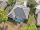 Aerial view of home featuring a screened pool enclosure and a well-maintained roof and lawn at 5351 Championship Cup Ln, Spring Hill, FL 34609