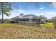 Rear exterior of home with a screened lanai, a neutral color scheme, and views of the backyard at 5351 Championship Cup Ln, Spring Hill, FL 34609