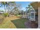 View of the backyard with mature landscaping, a screened enclosure, and a golf course beyond the property line at 5351 Championship Cup Ln, Spring Hill, FL 34609