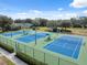 Aerial view showcasing well-maintained tennis courts with vibrant blue surfaces and green surroundings at 5351 Championship Cup Ln, Spring Hill, FL 34609