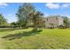 Spacious backyard featuring lush green grass, mature trees, patio set, and a black metal fence at 5412 Hammock View Ln, Apollo Beach, FL 33572