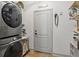 Modern laundry room featuring a stacked washer and dryer, shelves and white door at 5412 Hammock View Ln, Apollo Beach, FL 33572