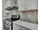 This kitchen features stainless steel appliances, a gray backsplash, and white cabinetry at 7399 Skylark Dr, Spring Hill, FL 34606