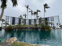 Exterior view of condo building with a pond and palm trees at 5855 Midnight Pass Rd # 416, Sarasota, FL 34242