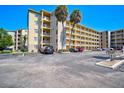 Tan multi-story building with balconies, palm trees, and ample parking at 3619 Lake Bayshore Dr # 402, Bradenton, FL 34205