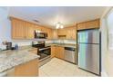 Well-lit kitchen featuring stainless steel appliances, tile flooring, granite counters, and wood cabinetry at 3411 Clark Rd # 212, Sarasota, FL 34231