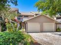 Two-story condo with a two-car garage, paver driveway, and lush landscaping at 5228 Landings Blvd # 202, Sarasota, FL 34231