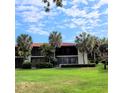 Two-story condo building with a red tile roof and palm trees at 3500 El Conquistador Pkwy # 142, Bradenton, FL 34210