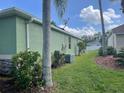 Side yard view of home showcasing green exterior, well-maintained lawn, and mature landscaping at 2910 122Nd E Ter, Parrish, FL 34219