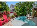 Relaxing kidney-shaped pool with red chairs and lush tropical landscaping at 4805 2Nd Ave, Holmes Beach, FL 34217