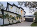 Two-story modern home with white exterior, dark roof, and palm trees at 2420 Floyd St, Sarasota, FL 34239