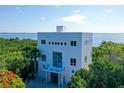 Stunning three-story white home with water views surrounded by lush tropical landscaping at 5444 Gulf Of Mexico Dr, Longboat Key, FL 34228