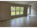 The spacious living room features tile flooring and natural light from a picture window and door at 2968 Yacolt Ave, North Port, FL 34286