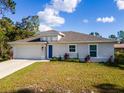 One-story house featuring a beige exterior, a grassy lawn, and a driveway at 1702 Rada Ln, North Port, FL 34288