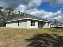 Rear view of the light green home, highlighting the backyard lawn and exterior architectural details at 5661 Gaffney Rd, North Port, FL 34286