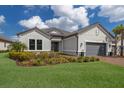 Inviting single-story home with lush landscaping, a brick driveway, and an attached two-car garage at 5510 Panella Ct, Palmetto, FL 34221