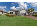 Beautiful home featuring a well-manicured lawn, brick driveway, and a two-car garage at 5510 Panella Ct, Palmetto, FL 34221