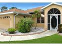 Attractive front entry with decorative screen door and well-manicured landscaping at 2111 Collingswood Blvd, Port Charlotte, FL 33948