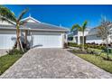 Paver driveway leads to a two car garage featuring manicured landscaping at 251 Okeeffe Cir, Bradenton, FL 34212