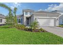 Two-story house with gray exterior, white garage door, and landscaped yard at 2528 Star Apple Way, Sarasota, FL 34240