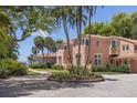 Pink stucco home with circular driveway and tropical landscaping at 4511 Bay Shore Rd, Sarasota, FL 34234